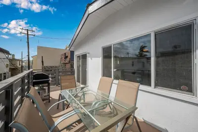 a balcony with a glass table and chairs at 2 Bedroom Upstairs with Balcony Steps from the Sand in Newport Beach