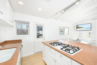 a kitchen with white cabinets and a stove top oven at 5 Bedroom Duplex 1 minute Walk to the Ocean in Newport Beach