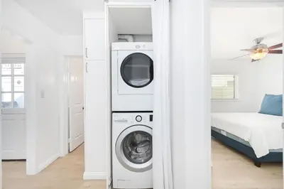 a washer and dryer in a room with a bed at 5 Bedroom Duplex 1 minute Walk to the Ocean in Newport Beach