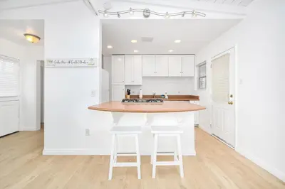 a kitchen with white cabinets and a counter with stools at Renovated 3 Bedroom Home on 41st-1 min walk to Beach in Newport Beach