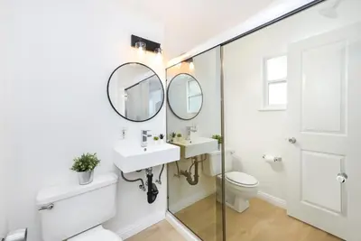 a bathroom with a sink and mirror and a toilet at Renovated 3 Bedroom Home on 41st-1 min walk to Beach in Newport Beach