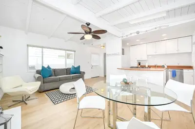 a living room with a glass table and white chairs at Renovated 3 Bedroom Home on 41st-1 min walk to Beach in Newport Beach