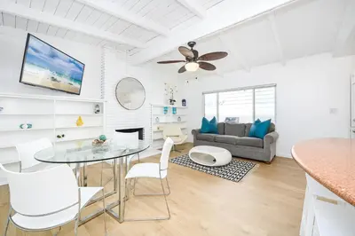 a white living room with a glass table and chairs at Renovated 3 Bedroom Home on 41st-1 min walk to Beach in Newport Beach