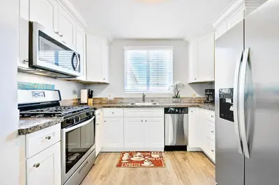 a kitchen with white cabinets and stainless steel appliances at 4 Bedroom Across from the Beach and Boardwalk in Newport Beach