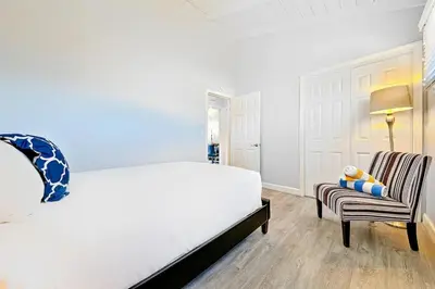 a bedroom with a white bed and a chair at 4 Bedroom Across from the Beach and Boardwalk in Newport Beach