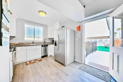 a kitchen with white cabinets and a stainless steel refrigerator at 4 Bedroom Across from the Beach and Boardwalk in Newport Beach