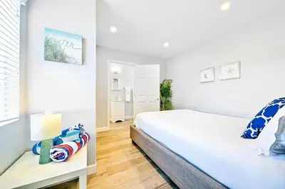 a white bedroom with a bed and a table at Duplex Across the Street from Beach & Boardwalk in Newport Beach