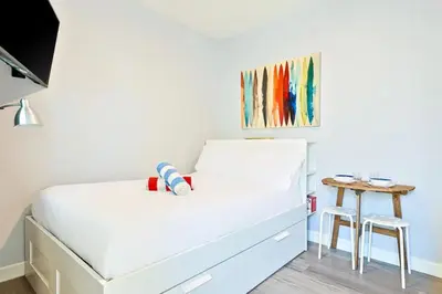 a small bedroom with a white bed and a table at Duplex Across the Street from Beach & Boardwalk in Newport Beach