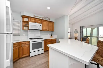 a kitchen with white appliances and wooden cabinets at Multi Level Oceanfront Home With Oceanviews and Private Patio on the Boardwalk in Newport Beach