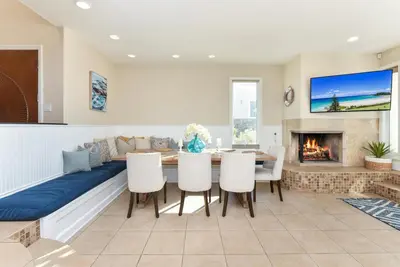 a living room with a dining table and a fireplace at Multi Level Oceanfront Home With Oceanviews and Private Patio on the Sand in Newport Beach