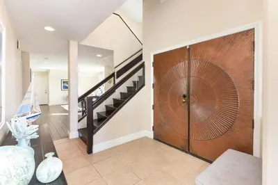 a large wooden door in a living room with a staircase at Multi Level Oceanfront Home With Oceanviews and Private Patio on the Sand in Newport Beach