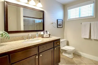 a bathroom with a sink and a toilet and a mirror at Multi Level Oceanfront Home With Oceanviews and Private Patio on the Sand in Newport Beach
