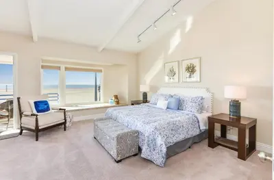 a bedroom with a bed and a chair and a window at 7 Bedroom Oceanfront Home & Back House in Newport Beach