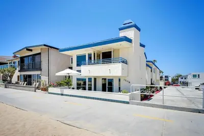 a large white building with an umbrella on a street at 7 Bedroom Oceanfront Home & Back House in Newport Beach