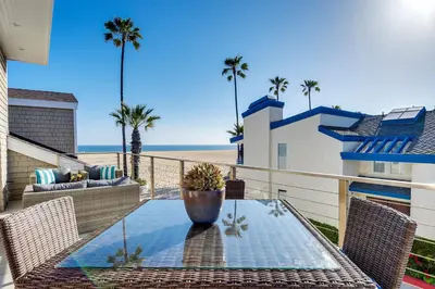 a patio with a table and chairs and the beach at New Renovated Beach Home with Ocean Views in Newport Beach