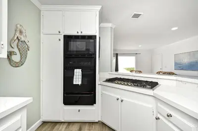 a kitchen with white cabinets and a black stove top oven at Updated Home with Patio on the Boardwalk near 15th St in Newport Beach