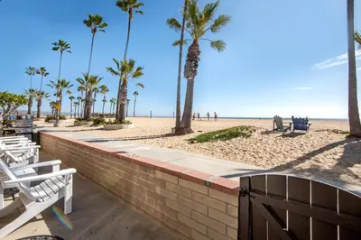 a brick wall next to a beach with palm trees at Updated Home with Patio on the Boardwalk near 15th St in Newport Beach