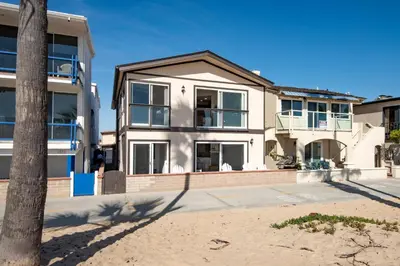 a house with a palm tree in front of it at Updated Home with Patio on the Boardwalk near 15th St in Newport Beach