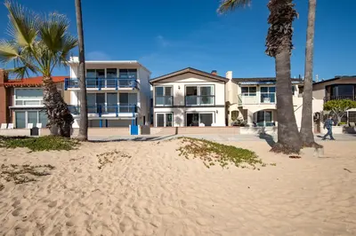 a building on the beach with palm trees in front at Updated Home with Patio on the Boardwalk near 15th St in Newport Beach