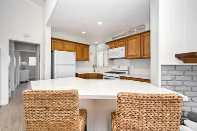 a kitchen with a white counter and two chairs at Oceanfront Triplex on Boardwalk with Ocean Views and Patio in Newport Beach