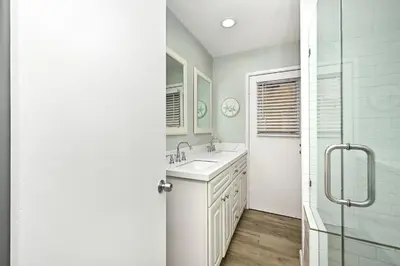 a white bathroom with a sink and a shower at Oceanfront Triplex on Boardwalk with Ocean Views and Patio in Newport Beach