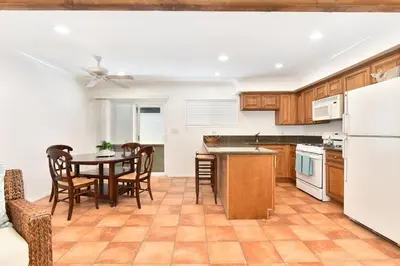 a kitchen with a table and chairs and a kitchen with white appliances at Updated Home on the Boardwalk with Private Rear Unit in Newport Beach