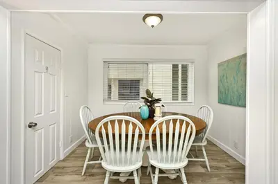 a dining room with a wooden table and white chairs at Updated Home on the Boardwalk with Private Rear Unit in Newport Beach