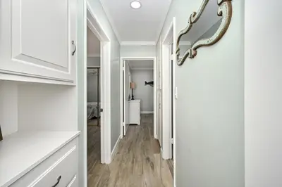 a hallway with white walls and wood floors and a mirror at Updated Home on the Boardwalk with Private Rear Unit in Newport Beach