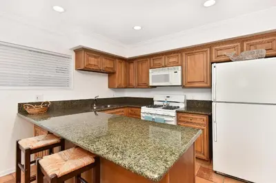 a kitchen with wooden cabinets and a white refrigerator at 2 Bedroom BACK Apt at OCEANFRONT HOME on 15th St in Newport Beach