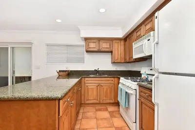 a kitchen with wooden cabinets and a white refrigerator at 2 Bedroom BACK Apt at OCEANFRONT HOME on 15th St in Newport Beach
