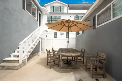 a table and chairs with an umbrella on a patio at TWO BEACHFRONT BUNGALOWS ON THE SAND IN Newport Beach in Newport Beach