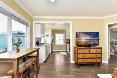 a kitchen with a table and a tv on a wall at TWO BEACHFRONT BUNGALOWS ON THE SAND IN Newport Beach in Newport Beach