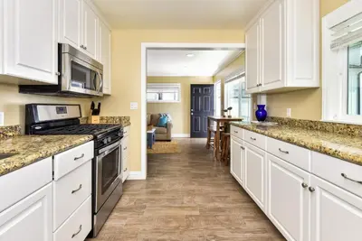 a kitchen with white cabinets and marble counter tops at TWO BEACHFRONT BUNGALOWS ON THE SAND IN Newport Beach in Newport Beach