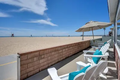 a row of chairs and an umbrella on the beach at TWO BEACHFRONT BUNGALOWS ON THE SAND IN Newport Beach in Newport Beach