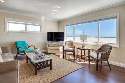 a living room with a couch and chairs and a television at TWO BEACHFRONT BUNGALOWS ON THE SAND IN Newport Beach in Newport Beach