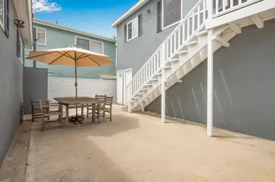 a table and chairs with an umbrella and stairs at Oceanfront Back Home with View of the Sea in Newport Beach