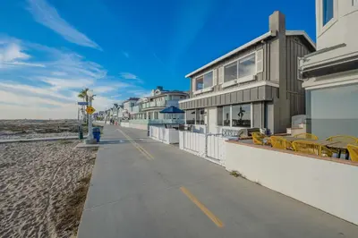 a sidewalk next to a beach with a building at Charming 2 Story and 4 Bedroom Home on the Boardwalk in Newport Beach