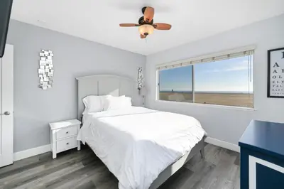 a white bedroom with a bed and a window at 5 Bedroom Duplex on the Boardwalk next to Balboa Pier in Newport Beach