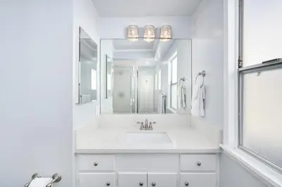 a white bathroom with a sink and a mirror at 5 Bedroom Duplex on the Boardwalk next to Balboa Pier in Newport Beach