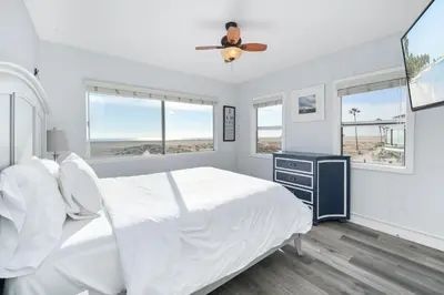 a white bedroom with a bed and a ceiling fan at 5 Bedroom Duplex on the Boardwalk next to Balboa Pier in Newport Beach
