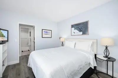 a white bedroom with a large bed and two lamps at 5 Bedroom Duplex on the Boardwalk next to Balboa Pier in Newport Beach