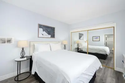 a bedroom with a large white bed and a mirror at 1 Bedroom Apartment in the back of our Oceanfront Home in Newport Beach