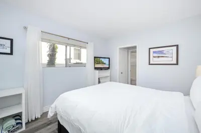a white bedroom with a bed and a window at 1 Bedroom Apartment in the back of our Oceanfront Home in Newport Beach