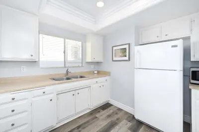 a kitchen with white cabinets and a white refrigerator at 1 Bedroom Apartment in the back of our Oceanfront Home in Newport Beach