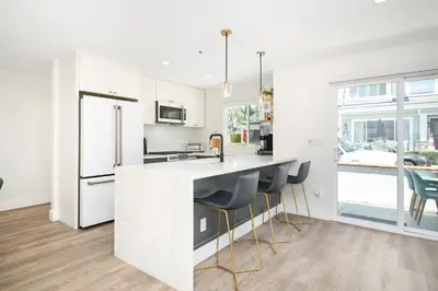 a kitchen with white cabinets and a counter with stools at Perfect Renovated and Modern Duplex on Balboa Island in Newport Beach