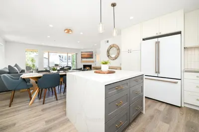 a kitchen and dining room with white cabinets and a table at Perfect Renovated and Modern Duplex on Balboa Island in Newport Beach