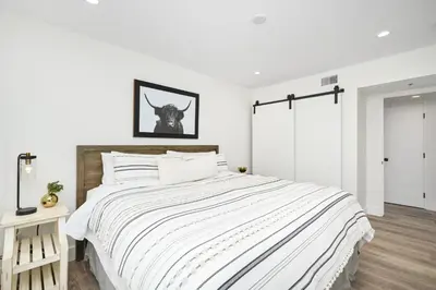 a white bedroom with a large bed with a wooden headboard at 4 bedroom Renovated Home on Balboa Island in Newport Beach