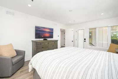 a white bedroom with a bed and a chair at 4 bedroom Renovated Home on Balboa Island in Newport Beach