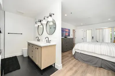 a bedroom with a bed and a sink and mirrors at 4 bedroom Renovated Home on Balboa Island in Newport Beach