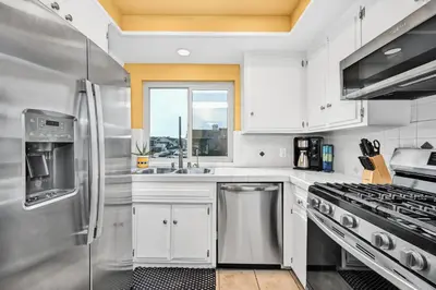 a kitchen with white cabinets and stainless steel appliances at Spanish Castle By The Sea in Newport Beach in Newport Beach